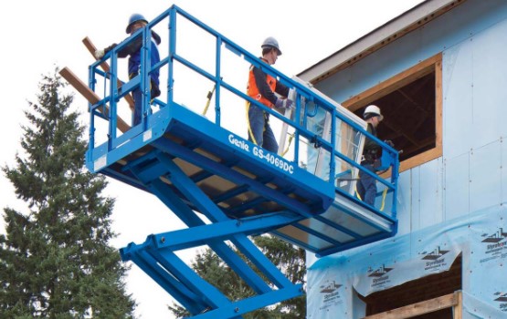 tres personas con equipo de protección instalando la ventana de un segundo piso sobre la canasta de una plataforma de elevación azul
